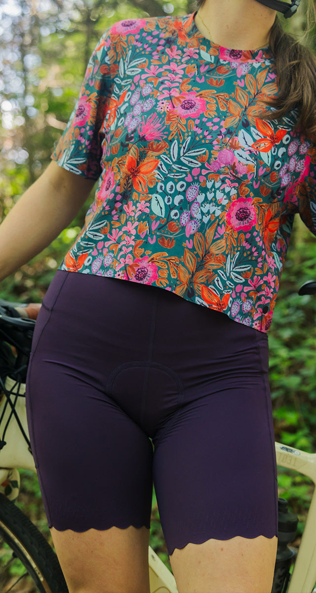 Mobile Version - Person wearing a colorful floral cycling jersey and dark shorts outdoors.