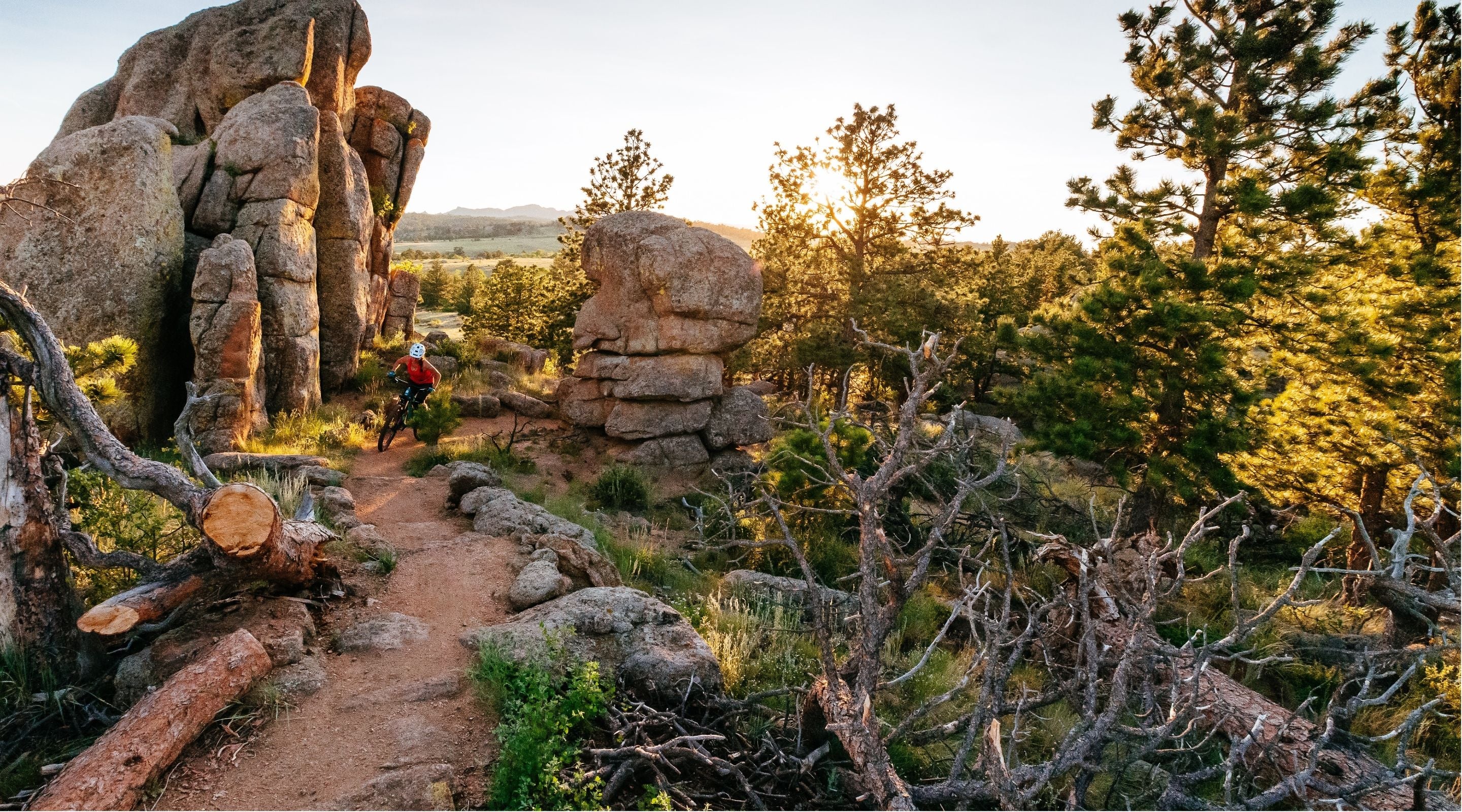 Person biking on a trail through rocky landscape with large boulders