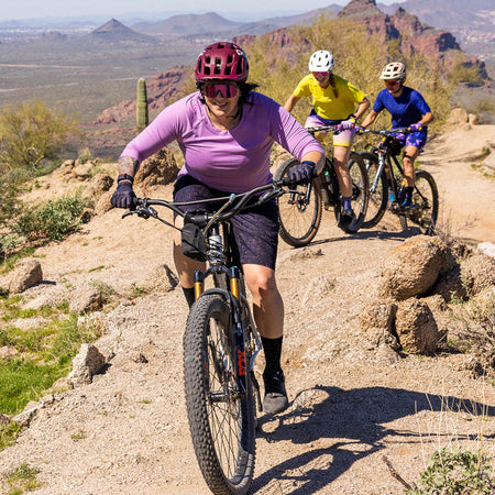 Three women mountain bikers riding a trail in the desert